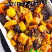 Rectangular dish with cooked carrots, dried fruits, and root vegetables in sauce, topped with fresh herbs. Text: “Slow Cooker Carrots with Dried Fruits.”.