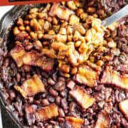 Cast iron skillet of baked beans with bacon strips on top and a spoon scooping some out. Overlay text: “Smoked Baked Beans.”.