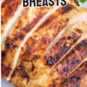 Sliced smoked chicken breast with grill marks on a white plate, garnished with green herb. Text overlay: “Traeger Smoked Chicken Breasts.”.